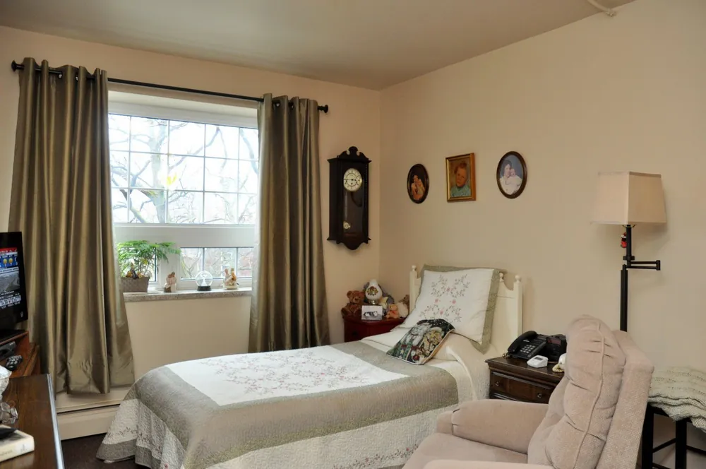 Bright suite bedroom with a single bed, wall clock and large window