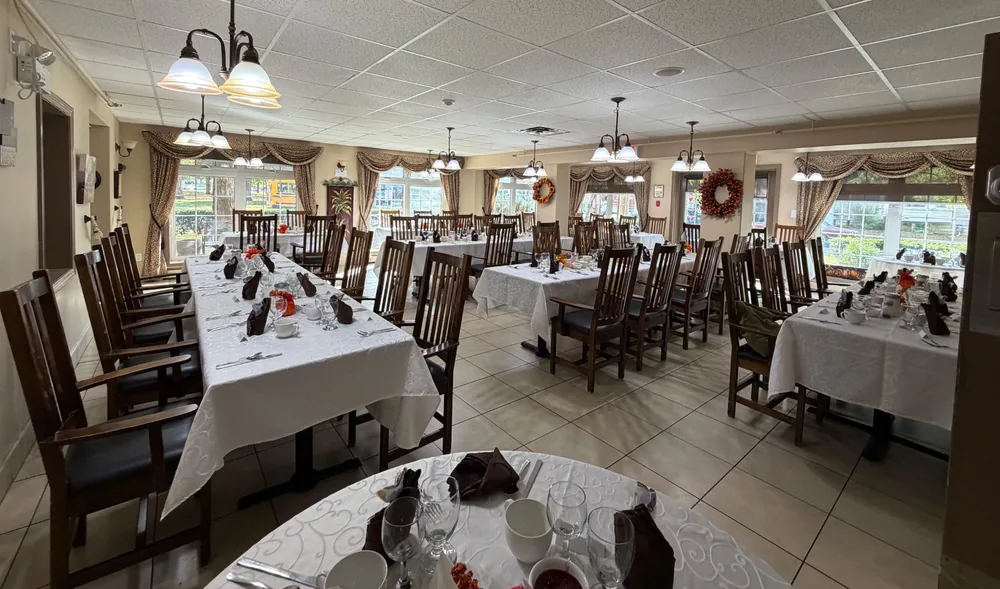 Parkview dining room set for Thanksgiving dinner with white tablecloths, folded napkins and autumn wreaths