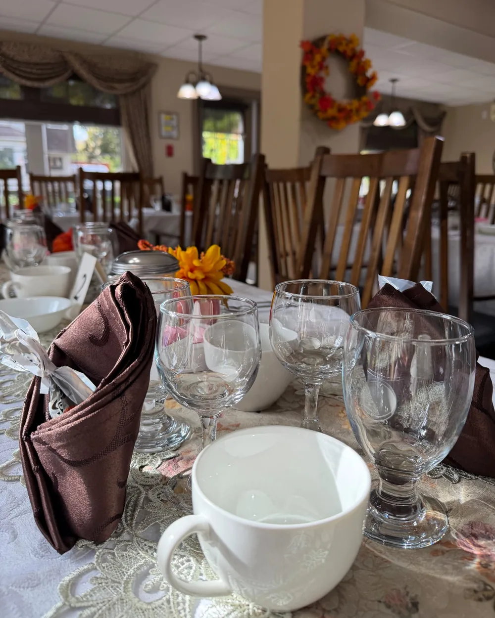 Close-up of glasses, a coffee cup and a folded napkin on a table set for Thanksgiving dinner