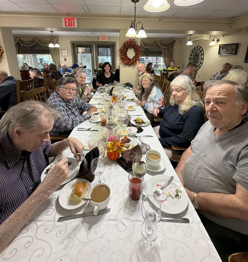 Residents and guests eating at a long table in the Parkview dining room during Thanksgiving dinner