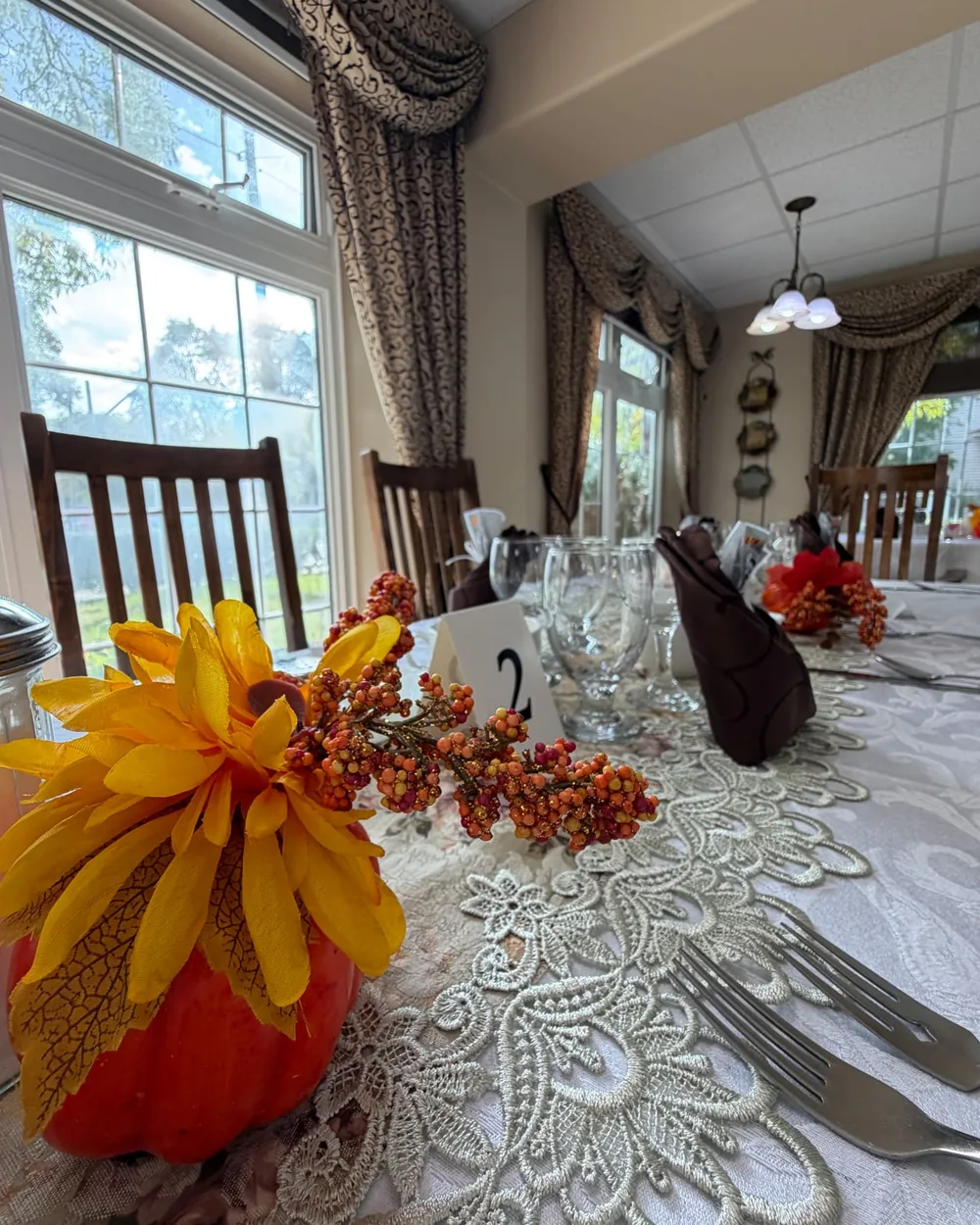 Pumpkin centrepiece with a yellow flower and autumn berries on a lace table runner