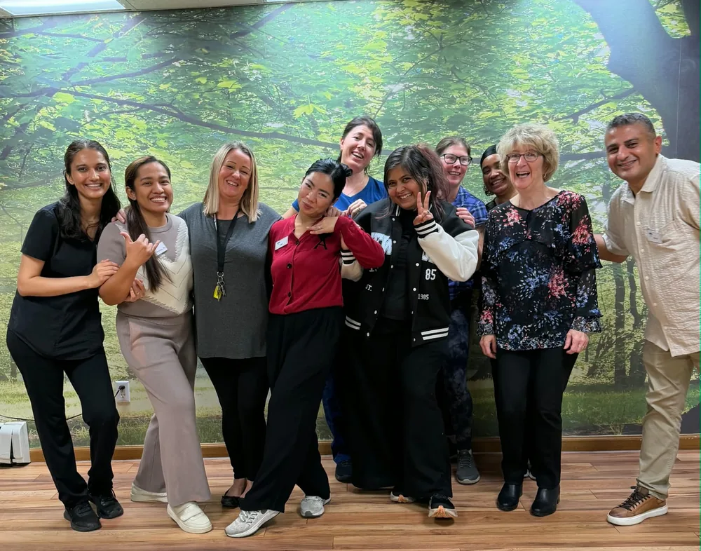 Ten Parkview Retirement Home staff members smiling together in front of a forest mural